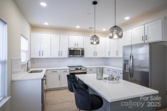 kitchen featuring white cabinets, appliances with stainless steel finishes, a center island, and sink