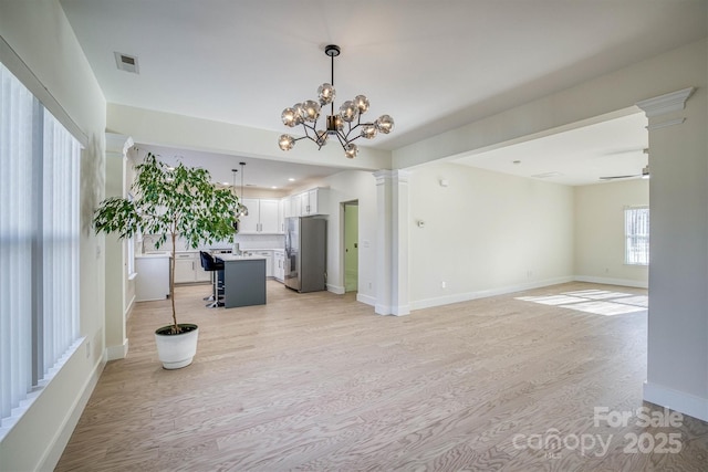 unfurnished living room featuring light hardwood / wood-style floors and ceiling fan with notable chandelier