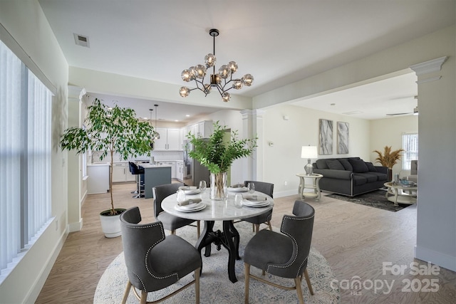 dining space with ceiling fan with notable chandelier and light hardwood / wood-style flooring