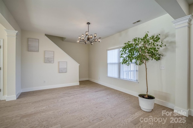 interior space featuring decorative columns, light hardwood / wood-style floors, and a notable chandelier