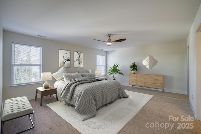 bedroom featuring ceiling fan, light hardwood / wood-style flooring, and multiple windows