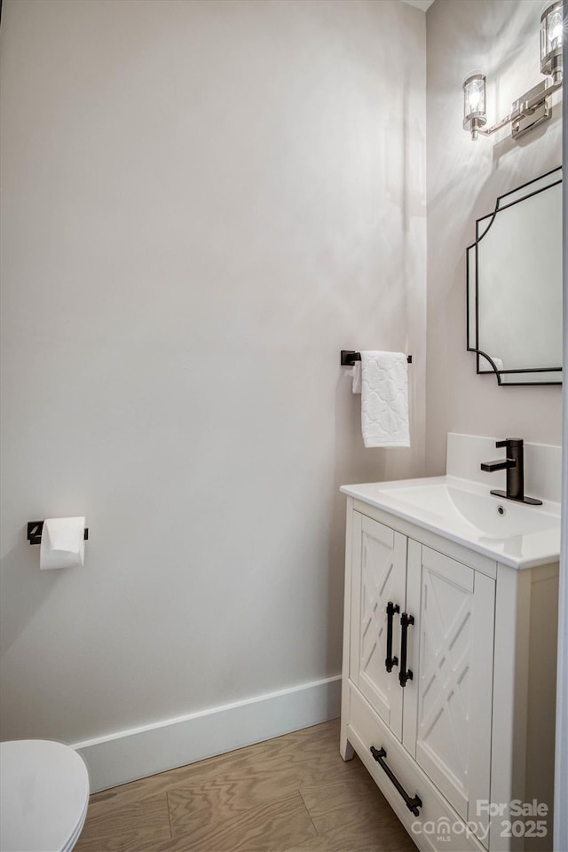 bathroom with hardwood / wood-style floors, vanity, and toilet