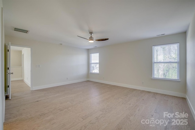 spare room featuring ceiling fan, a wealth of natural light, and light hardwood / wood-style flooring