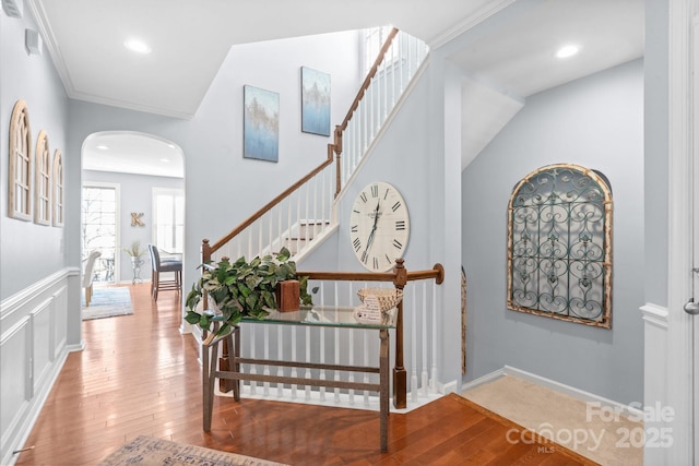 stairway with hardwood / wood-style floors and ornamental molding