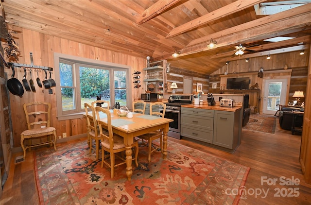 dining space featuring wooden walls, lofted ceiling with skylight, ceiling fan, and wooden ceiling