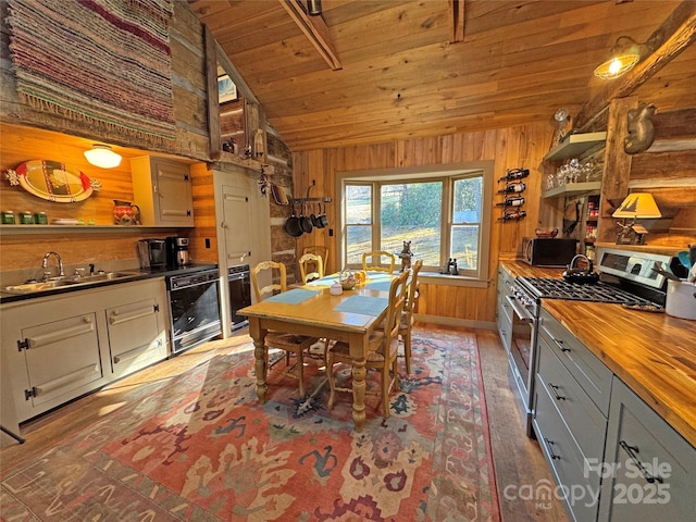 kitchen featuring wooden ceiling, lofted ceiling, sink, stainless steel gas stove, and butcher block counters