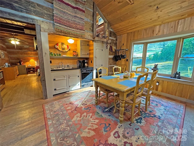 dining area featuring ceiling fan, wooden ceiling, wood walls, wood-type flooring, and lofted ceiling