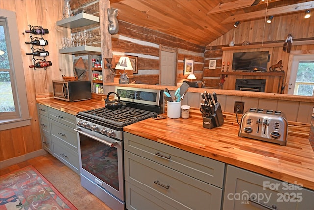 kitchen with wooden ceiling, lofted ceiling with beams, wooden walls, gray cabinets, and high end stove