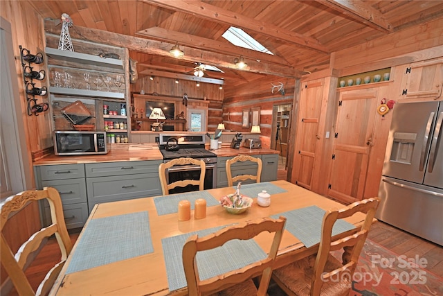 dining area featuring a skylight, wood walls, beamed ceiling, and wooden ceiling