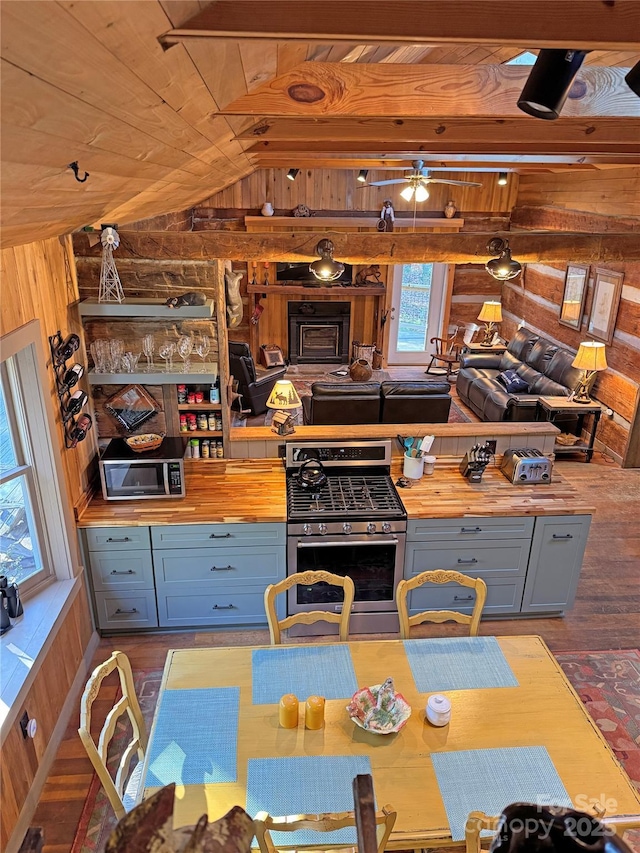 dining area featuring ceiling fan, wooden walls, wooden ceiling, hardwood / wood-style floors, and lofted ceiling