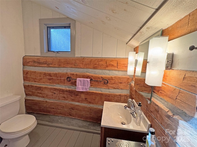 bathroom with hardwood / wood-style flooring, vanity, wood walls, and lofted ceiling