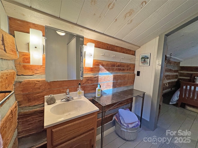 bathroom featuring vanity, wood walls, and vaulted ceiling