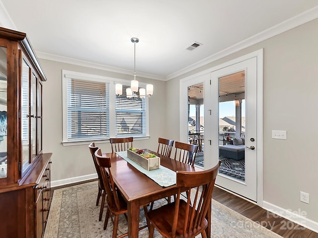 dining area featuring dark hardwood / wood-style flooring, a chandelier, and crown molding