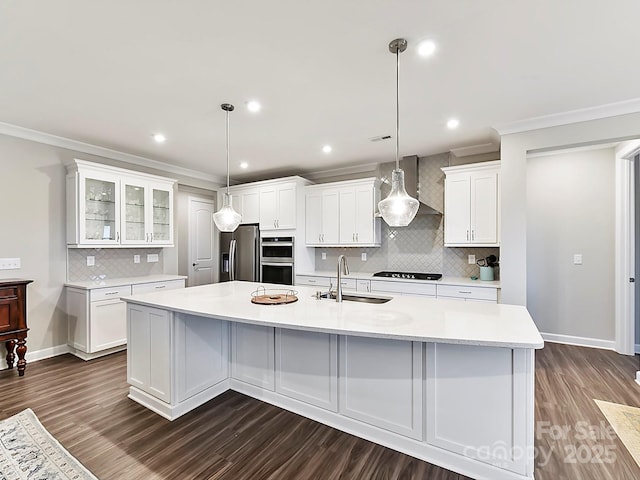 kitchen with a large island, white cabinets, stainless steel appliances, wall chimney exhaust hood, and sink