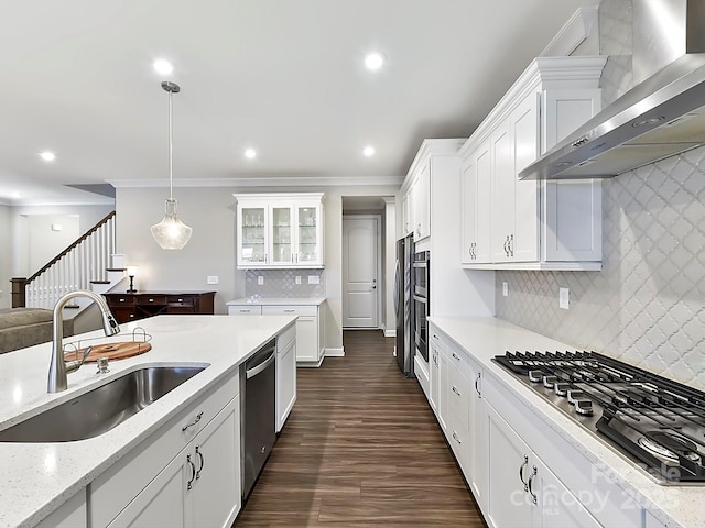 kitchen with sink, white cabinetry, wall chimney range hood, and hanging light fixtures