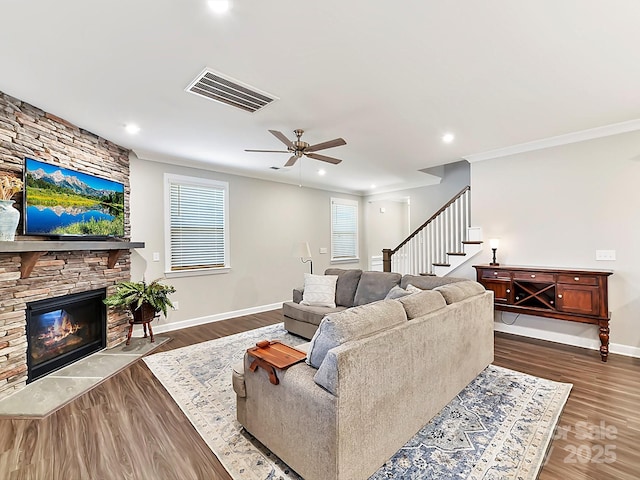 living room featuring a fireplace, dark wood-type flooring, ceiling fan, and crown molding