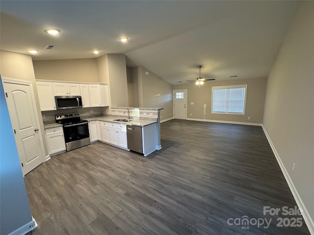 kitchen with sink, light stone countertops, appliances with stainless steel finishes, white cabinetry, and kitchen peninsula