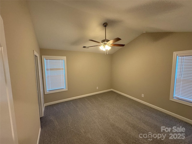 unfurnished room featuring dark colored carpet, ceiling fan, and vaulted ceiling