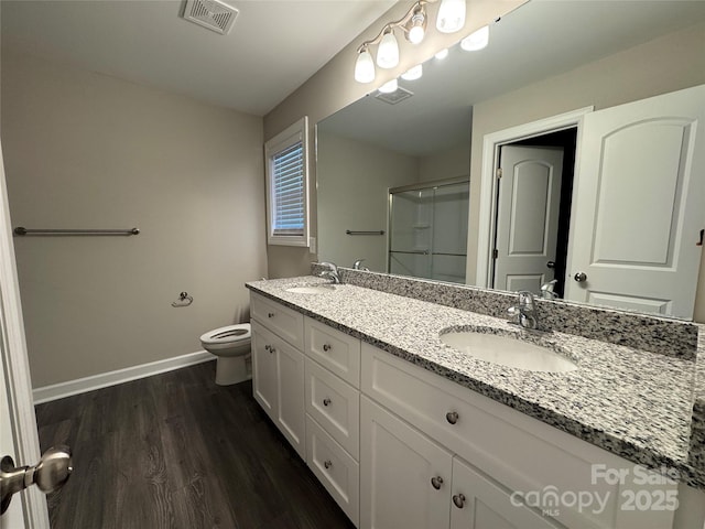 bathroom with hardwood / wood-style floors, vanity, toilet, and a shower with shower door