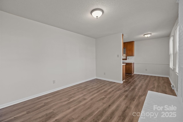 unfurnished living room featuring dark hardwood / wood-style flooring and a textured ceiling