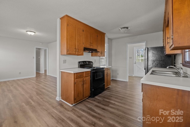 kitchen featuring a textured ceiling, sink, electric range, light hardwood / wood-style flooring, and fridge