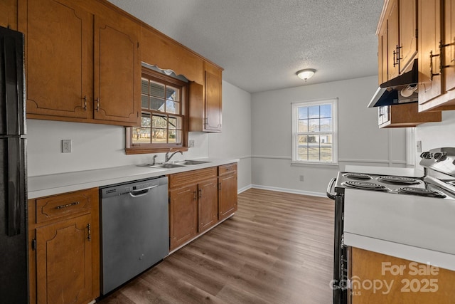 kitchen featuring stainless steel dishwasher, a textured ceiling, sink, wood-type flooring, and range with electric stovetop