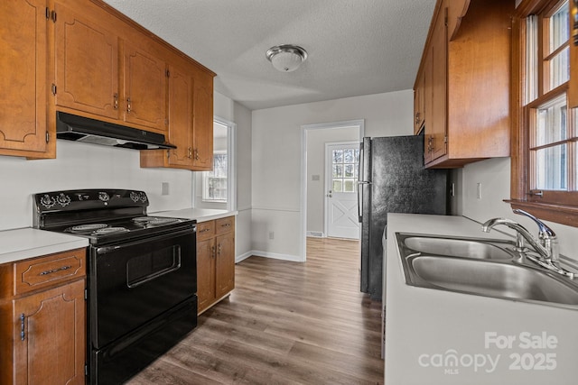 kitchen featuring hardwood / wood-style floors, black / electric stove, sink, a textured ceiling, and fridge