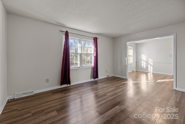 empty room with a textured ceiling and dark wood-type flooring