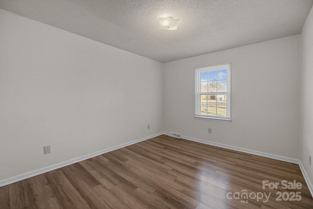 unfurnished room featuring a textured ceiling and dark hardwood / wood-style flooring