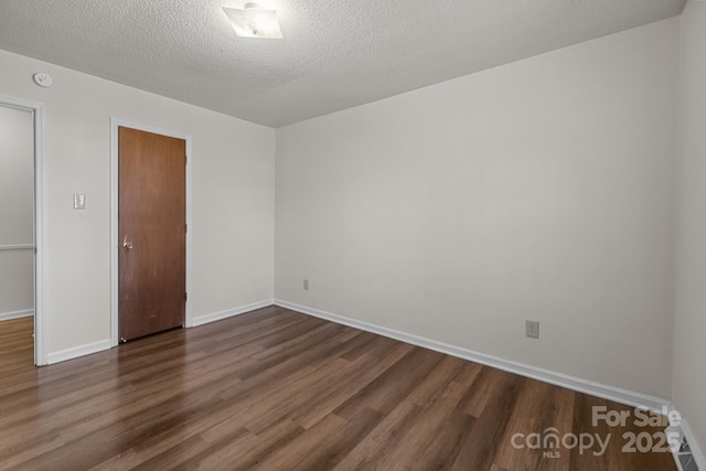 empty room with a textured ceiling and dark wood-type flooring