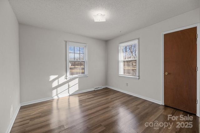 empty room with dark hardwood / wood-style flooring and a textured ceiling