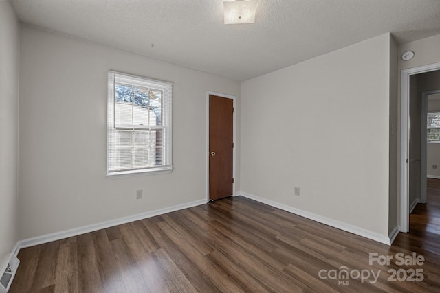 spare room with a textured ceiling and dark wood-type flooring