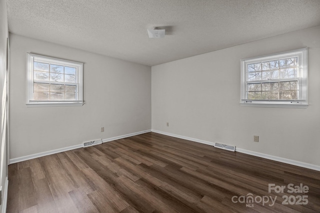 unfurnished room with dark hardwood / wood-style flooring and a textured ceiling