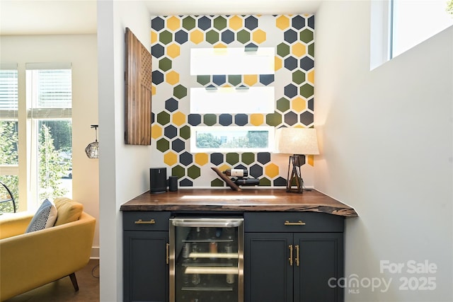 bar with wooden counters, wine cooler, and backsplash