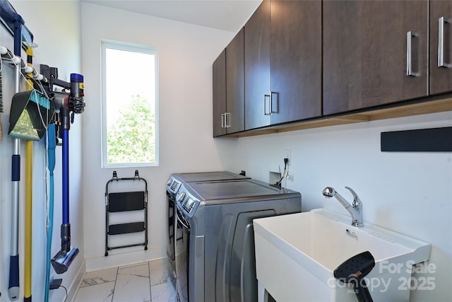 clothes washing area with cabinets, washer and clothes dryer, and sink