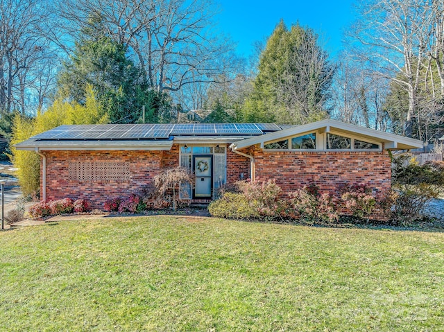 single story home with a front lawn and solar panels