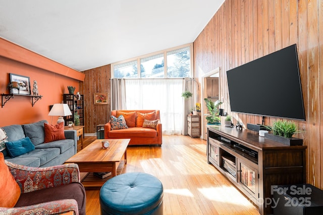 living room featuring light wood-type flooring and wood walls