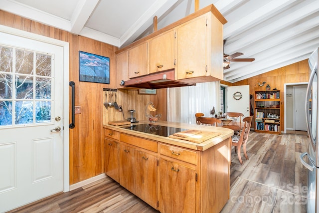 kitchen featuring black electric stovetop, lofted ceiling with beams, wood walls, light hardwood / wood-style flooring, and range hood