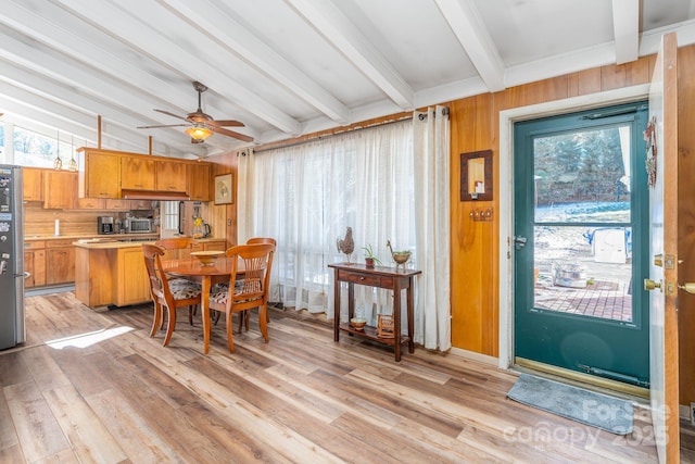 dining room with light wood-type flooring, ceiling fan, plenty of natural light, and lofted ceiling with beams