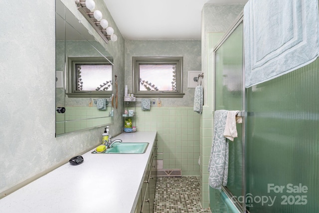 bathroom featuring tile walls, combined bath / shower with glass door, vanity, and tile patterned flooring