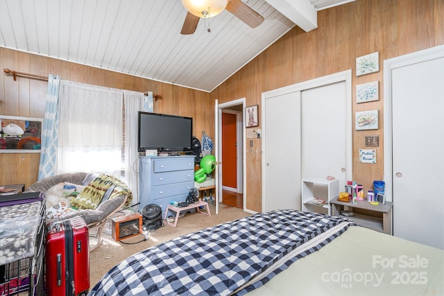 carpeted bedroom with ceiling fan, a closet, wood walls, and vaulted ceiling with beams