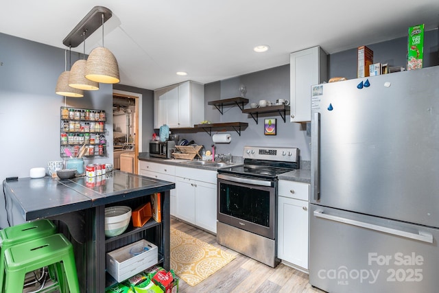 kitchen featuring pendant lighting, washer / dryer, stainless steel appliances, and white cabinetry