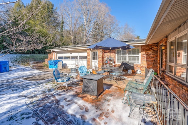 snow covered patio with area for grilling and a fire pit