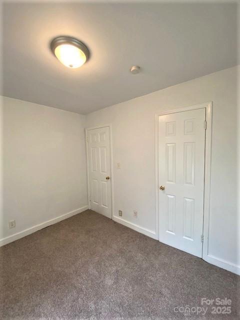 spare room with dark colored carpet