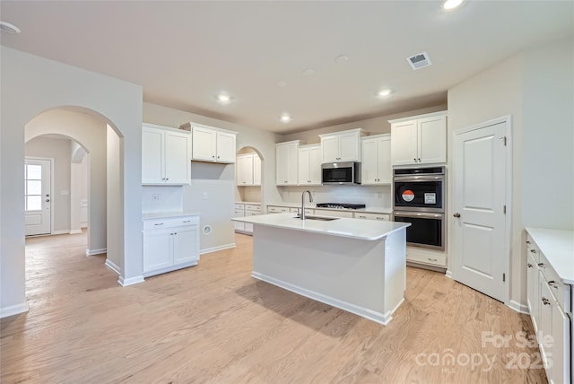 kitchen with sink, a kitchen island with sink, white cabinetry, and appliances with stainless steel finishes