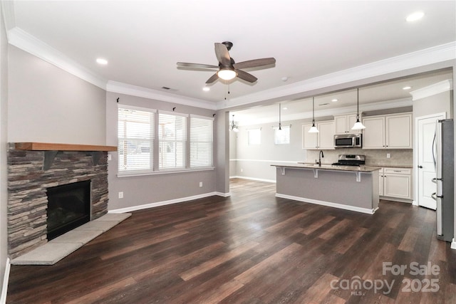 living room with ceiling fan, sink, a stone fireplace, dark hardwood / wood-style flooring, and ornamental molding