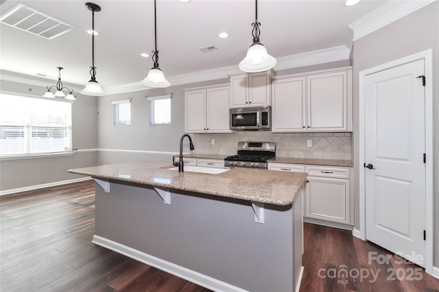 kitchen featuring a breakfast bar, a kitchen island with sink, sink, hanging light fixtures, and stainless steel appliances