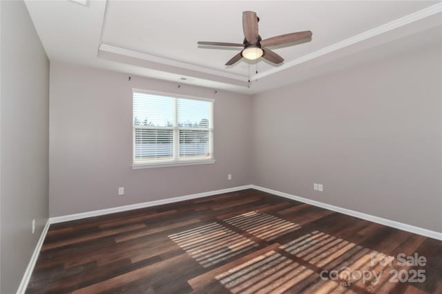 empty room featuring a tray ceiling, ceiling fan, dark hardwood / wood-style flooring, and ornamental molding