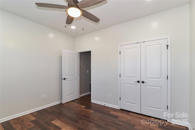 unfurnished bedroom with ceiling fan, a closet, and dark wood-type flooring