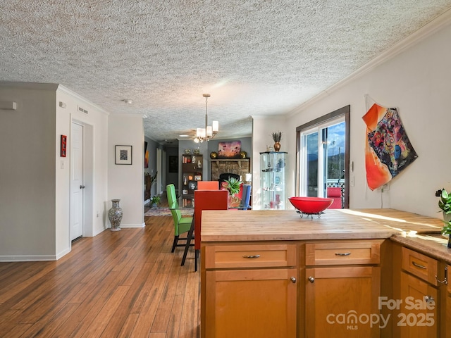 kitchen featuring a textured ceiling, wood counters, crown molding, and a fireplace